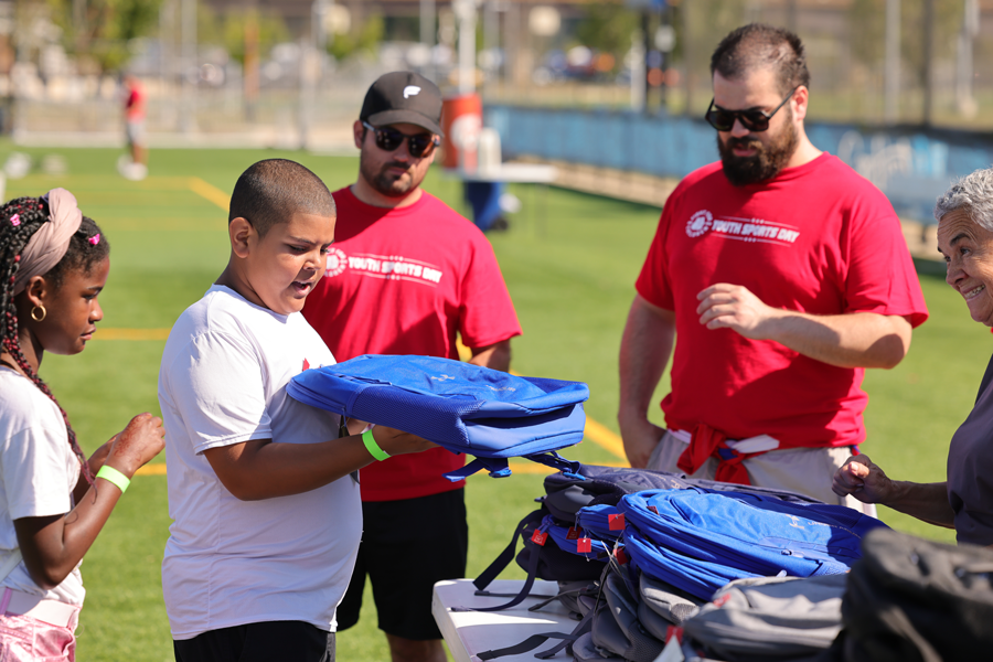 Children receiving free backpacks at the Fight For Children Youth Sports Day